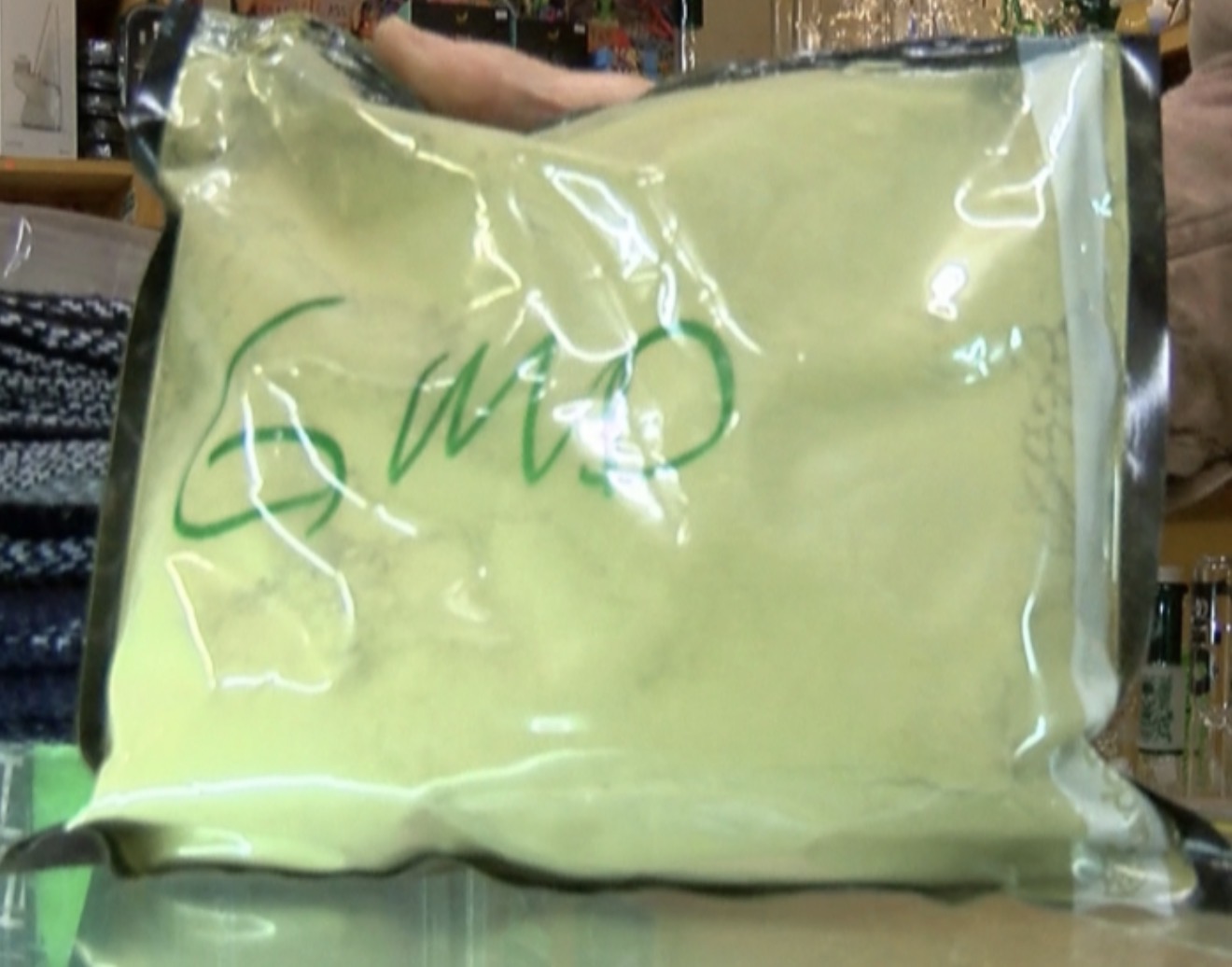 Clear bag containing light green powder with handwritten markings, bulk unlabeled material